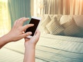 Woman hand hold and touch screen smart phone on vintage bedroom Royalty Free Stock Photo