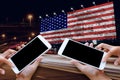 Woman hand hold and touch screen on smartphone or cellphone over blurred America flag on clacked wall background.