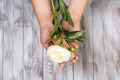 A woman hand hold a white peony flower. Light wood background. Top view. Royalty Free Stock Photo