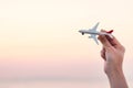 Woman hand holding airplane model in sunset sky and summer sea b Royalty Free Stock Photo