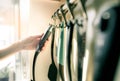 Woman hand holding black plastic handle of spatula. Woman cooking food in apartment kitchen. Cooking utensil set hanging on Royalty Free Stock Photo