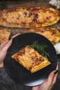 Woman hand holding black plate with fresh cooked yellow zucchini with meat , tomatoes , onions and garlic in a oven. Royalty Free Stock Photo