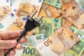 Woman hand holding black power plug over euro banknotes background. Power crisis and inflation. Concepts of increasing the energy Royalty Free Stock Photo