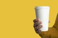 Woman hand holding a blank paper coffee cup on isolated yellow background.Mockup , banner template with copy space for text Royalty Free Stock Photo