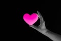 Woman hand holding blank pink heart on dark background