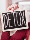 Woman hand holding board with detox sign
