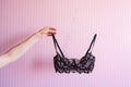 Woman hand holding bra on pink background. Lingerie in hands, fashion and sale concept. Royalty Free Stock Photo