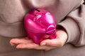 Woman hand holding bright pink pig money box close up. Economy, budget and savings concept. Royalty Free Stock Photo