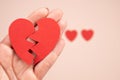 Woman hand holding broken paper red heart on pink background. Broken heart love relationship concept. Royalty Free Stock Photo