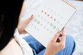 Asian woman hand holding calendar counting the date and checking her menstrual cycle planning for ovulation