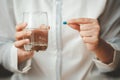 Woman hand holding capsule pill and glass of water Royalty Free Stock Photo