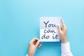 Woman hand holding card with the word you can do it  on blue background, studio shot. cheer and support quote. Royalty Free Stock Photo