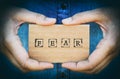 Woman hand holding cardboard card with word Fear. Denim backgrounds.