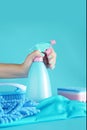 Woman hand holding cleaning spray blue plastic bottle detergent isolated on blue background with cleaning tools product supplies Royalty Free Stock Photo