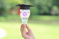 Woman hand holding cog inside in light bulb with graduates hat on natural green background, Education and Creative idea and Royalty Free Stock Photo