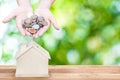 Woman hand holding coins house bank save money, green nature background