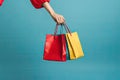 Woman hand holding colorful shopping bags on blue background. Consumerism concept, Female hand holding many colorful shopping bags Royalty Free Stock Photo