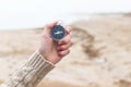 Woman hand holding compass against blurred seashore, beach. Hiking traveler equipment. Navigation for travel. Find way and