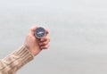 Woman hand holding compass against light blurred seascape. Hiking traveler equipment. Navigation for travel. Find way and