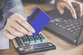 Woman hand holding credit card making payment on computer notebook with calculator Royalty Free Stock Photo