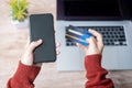 Woman hand holding credit card with using smartphone and laptop for online shopping while making orders at home. business, Royalty Free Stock Photo