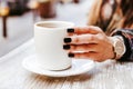 Woman hand holding a cup of coffee outdoors at coffee shop or cafe with blurred background Royalty Free Stock Photo