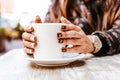 Woman hand holding a cup of coffee outdoors at coffee shop or cafe with blurred background Royalty Free Stock Photo