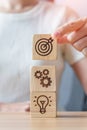 Woman hand holding dartboard above Gear and Lightbulb icon block. business planning process, goal, strategy, target, mission, Royalty Free Stock Photo