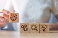 Woman hand holding dartboard above Gear, magnifying and Lightbulb icon block. business planning process, goal, strategy, target,