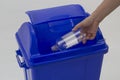 Woman hand holding empty bottle into the trash isolated on white