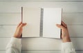 Woman hand holding empty open book on white wooden table. Empty paper page Royalty Free Stock Photo