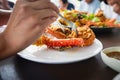 Woman hand holding fork dipping in piece of fried lobster shrimp with garlic on the plate