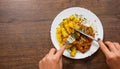 Woman hand holding fork and knife with Grilled chicken breast with potato in a plate on a wooden background Royalty Free Stock Photo