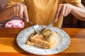 Woman hand holding fork and spoon and white plate with omelet potato, tomatoes parsley and feta cheese and bread on wooden table Royalty Free Stock Photo