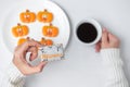 Woman hand holding funny Halloween Cookie during drinking coffee. Happy Halloween day, Trick or Threat, Hello October, fall autumn Royalty Free Stock Photo