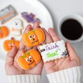 Woman hand holding funny Halloween Cookie during drinking coffee. Happy Halloween day, Trick or Threat, Hello October, fall autumn Royalty Free Stock Photo