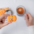 Woman hand holding funny Halloween Cookie during drinking coffee. Happy Halloween day, Trick or Threat, Hello October, fall autumn Royalty Free Stock Photo