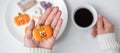 Woman hand holding funny Halloween Cookie during drinking coffee. Happy Halloween day, Trick or Threat, Hello October, fall autumn Royalty Free Stock Photo