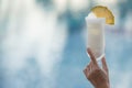 Woman hand holding a glass of cocktail on the edge of the pool Royalty Free Stock Photo