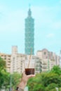 Woman hand holding a glass of ice coffee against Taipei city background