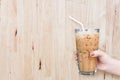 woman hand holding the glass iced coffee on wooden background