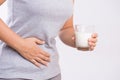 Woman hand holding glass of milk having bad stomach ache because of Lactose intolerance. health problem with dairy food products,