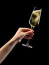 Woman hand holding glass of sparkling champagne  on black. Royalty Free Stock Photo