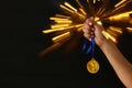 Woman hand holding gold medal against black background with glitter overlay. Award and victory concept. Royalty Free Stock Photo