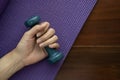 woman hand holding green dumbbell on yoga mat on wood table background Royalty Free Stock Photo