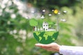 Woman hand holding green world with model house and model family on natural green background, We love the world of ideas Royalty Free Stock Photo