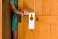 Woman hand holding and hangs signboard do not disturb on the door in hotel