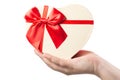 Woman hand holding heart shaped present box with red ribbon isolated on white background. Royalty Free Stock Photo