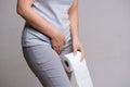 Woman hand holding her crotch lower abdomen and tissue or toilet paper roll. Disorder, Diarrhea, incontinence. Healthcare concept Royalty Free Stock Photo