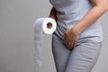 Woman hand holding her crotch lower abdomen and tissue or toilet paper roll. Disorder, Diarrhea, incontinence. Healthcare concept Royalty Free Stock Photo